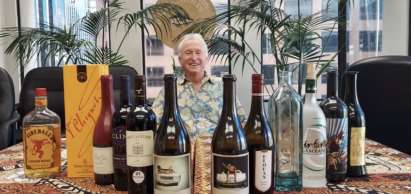 Smiling man behind table of assorted alcohol bottles