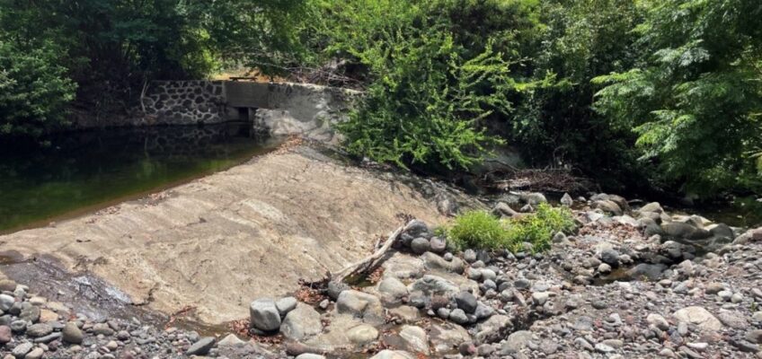 Small concrete dam on rocky streambed