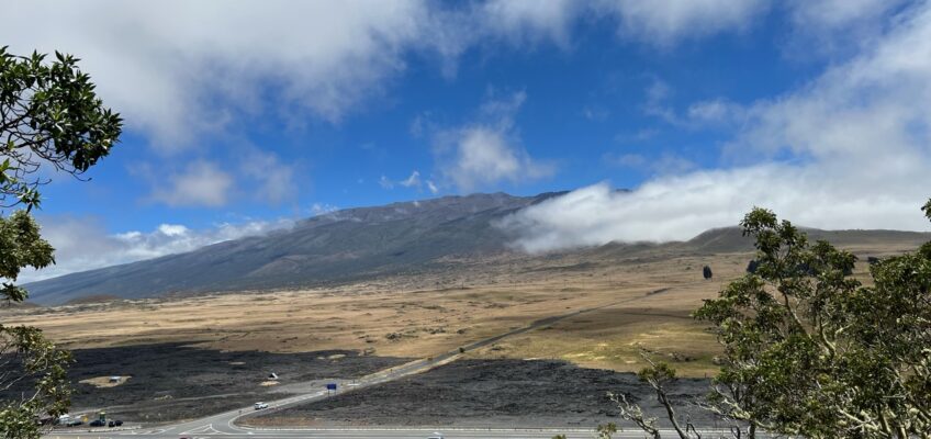 Road through volcanic landscape toward cloud-capped mountain