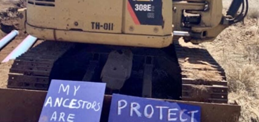 Excavator with protest signs about ancestral burial