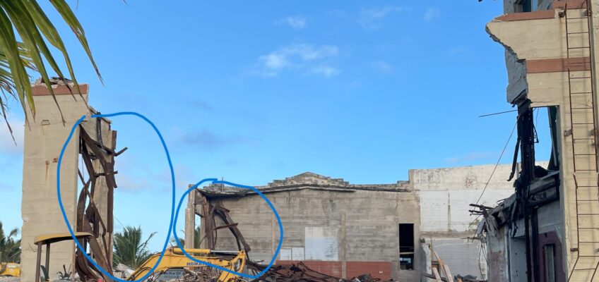 Partially demolished concrete building with excavator