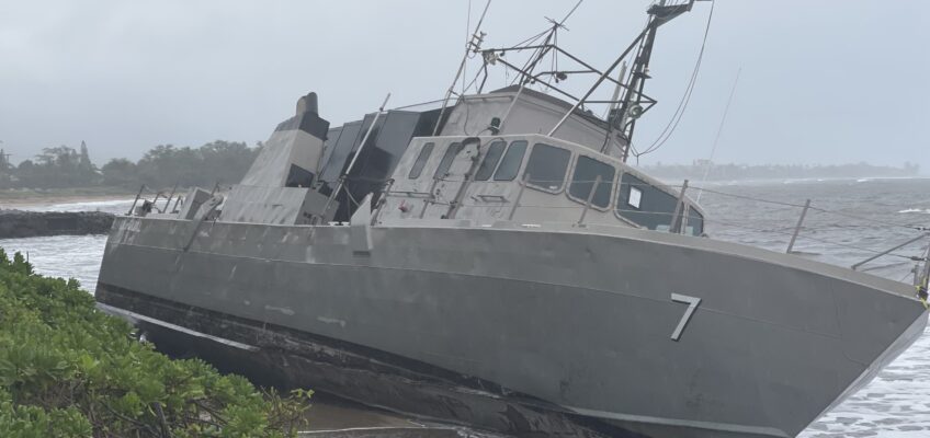 Beached gray patrol boat leaning on shore